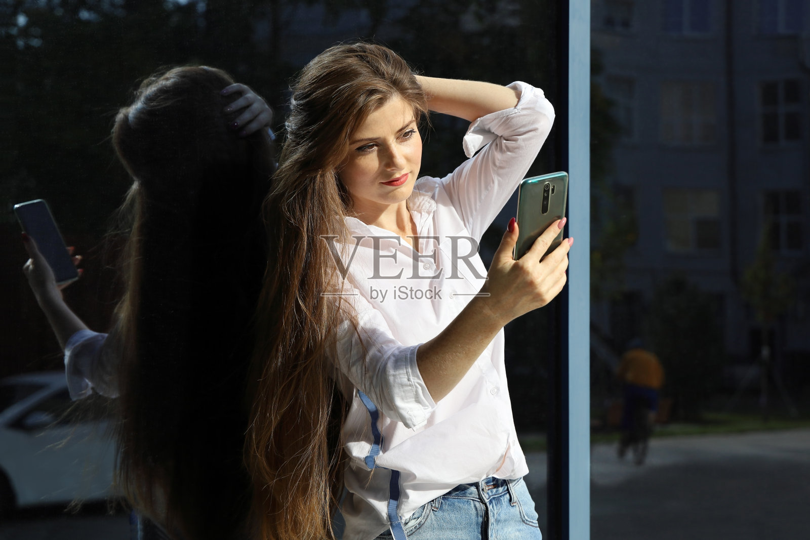 年轻漂亮的长发女子看着智能手机屏幕照片摄影图片