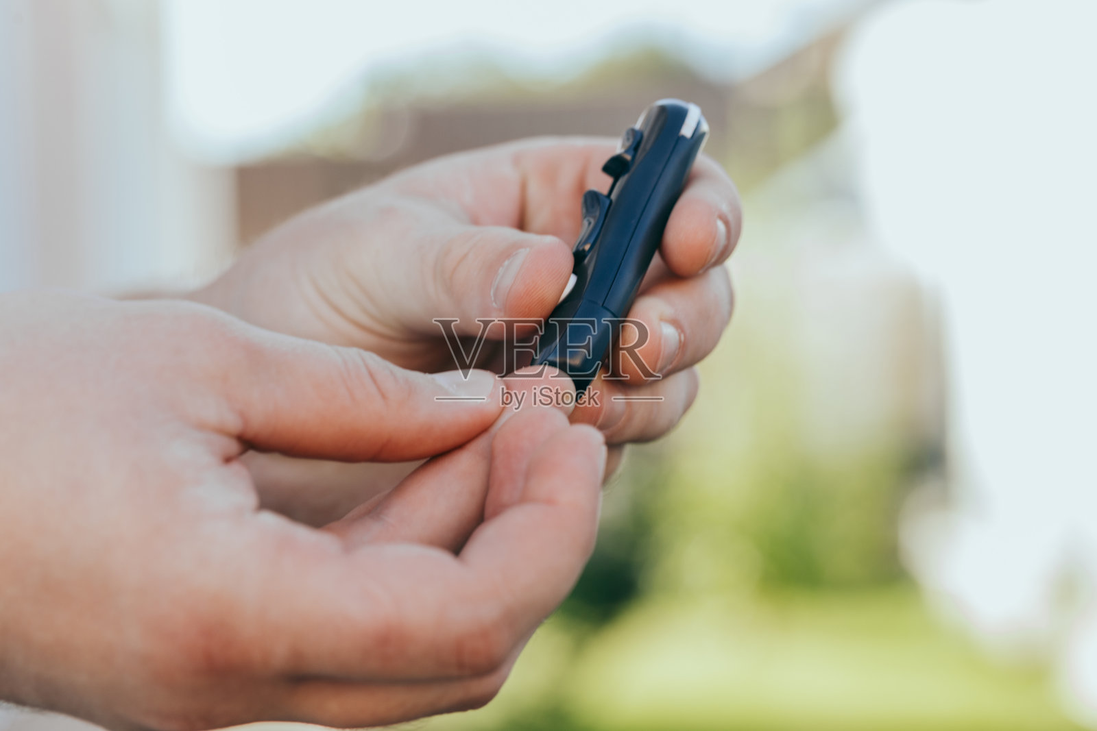 医学,糖尿病,血糖,保健和人的概念-近距离一个男人的手使用柳叶刀在他的手指检查血糖仪与复制空间的文本照片摄影图片