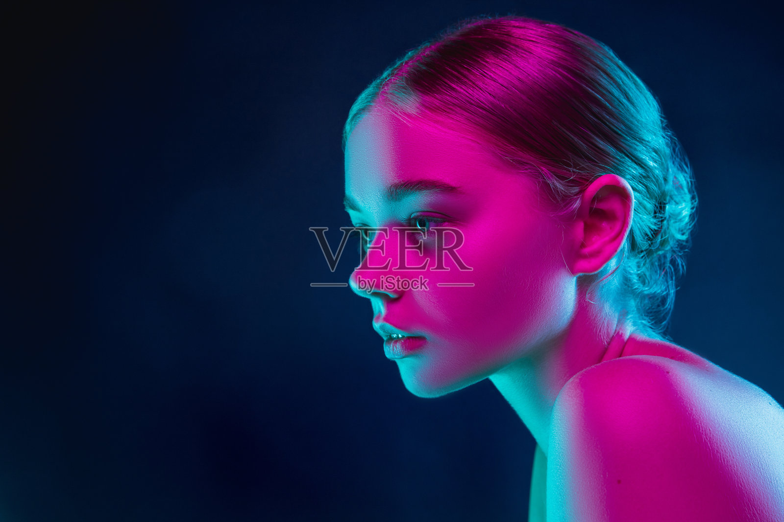 女时装模特的肖像在霓虹灯在黑暗的工作室背景。照片摄影图片