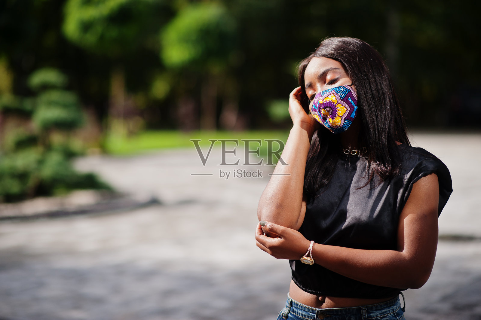 时尚的非裔美国女性,戴着手工制作的面具在户外摆姿势。新的正常的生活。照片摄影图片