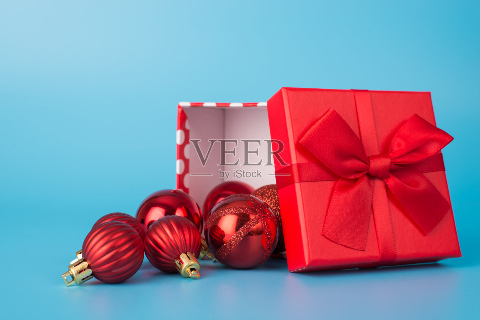 圣诞快乐。近距离的照片红色蝴蝶结和许多树的小玩意在里面孤立在蓝色的光背景照片摄影图片