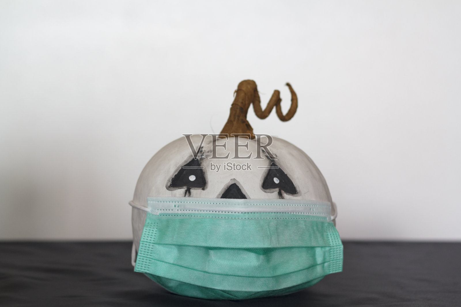 戴着保护面罩的南瓜。2019冠状病毒病大流行期间万圣节的概念照片摄影图片