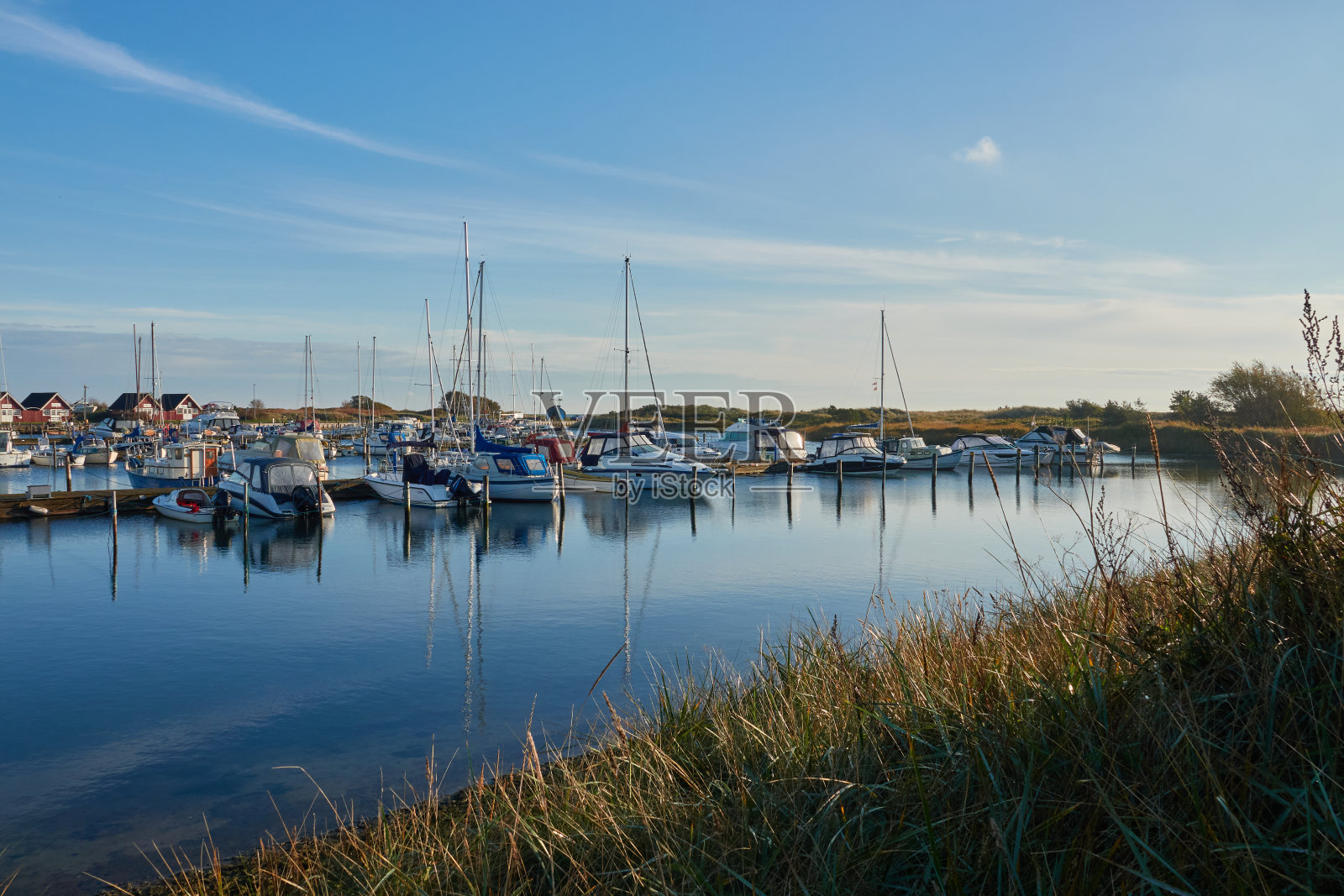 丹麦码头的正面视图,水面上的船只都牢牢地固定在码头上。一些小木屋在后面。丹麦、侯。照片摄影图片