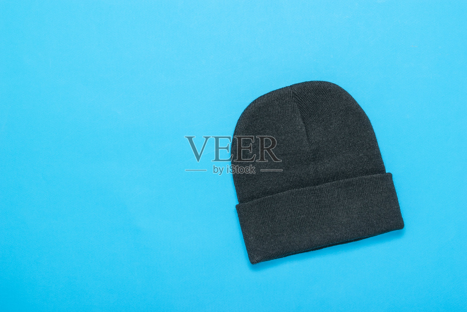 蓝色背景的黑色针织女帽。照片摄影图片