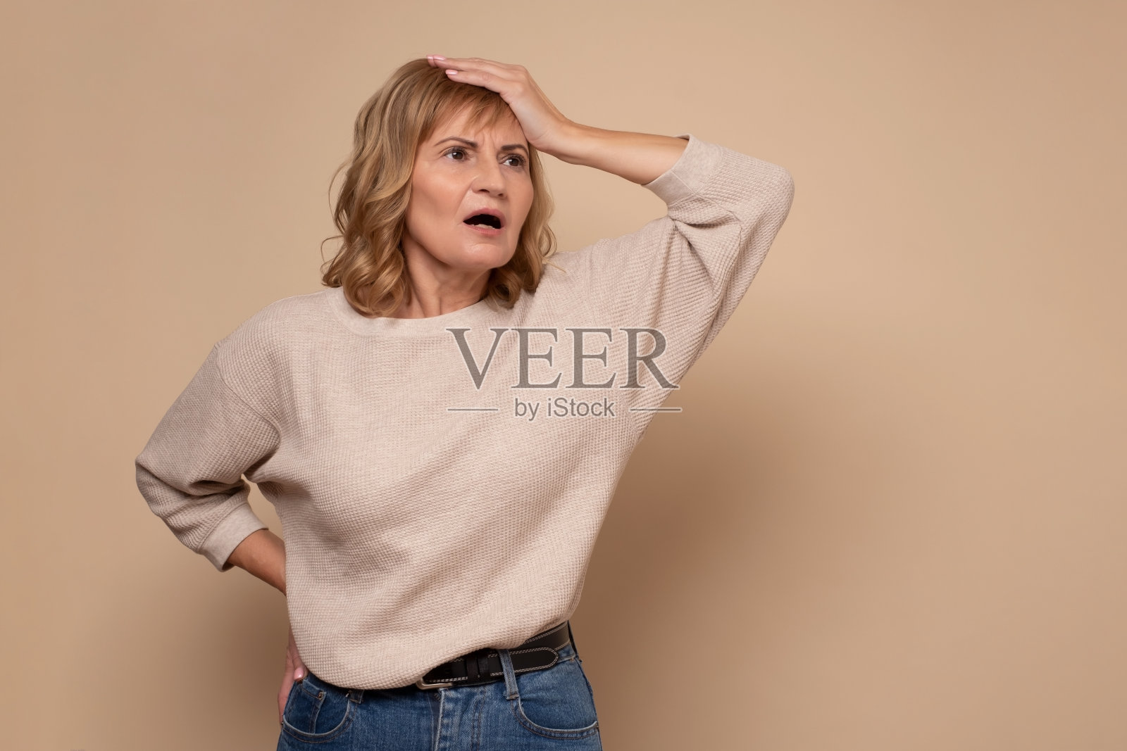 迷茫的成熟女人把手放在头上,忘记了重要的会议。照片摄影图片