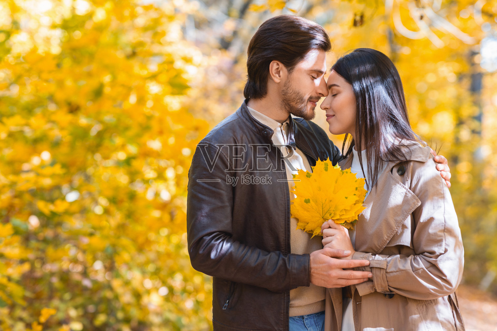 男人和女人闭着眼睛拥抱在秋天的森林里照片摄影图片