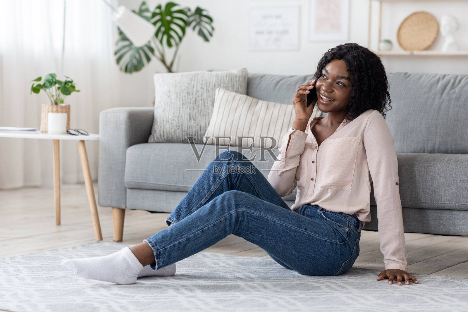 家里的消遣方式。快活的非洲女人在客厅里打电话照片摄影图片