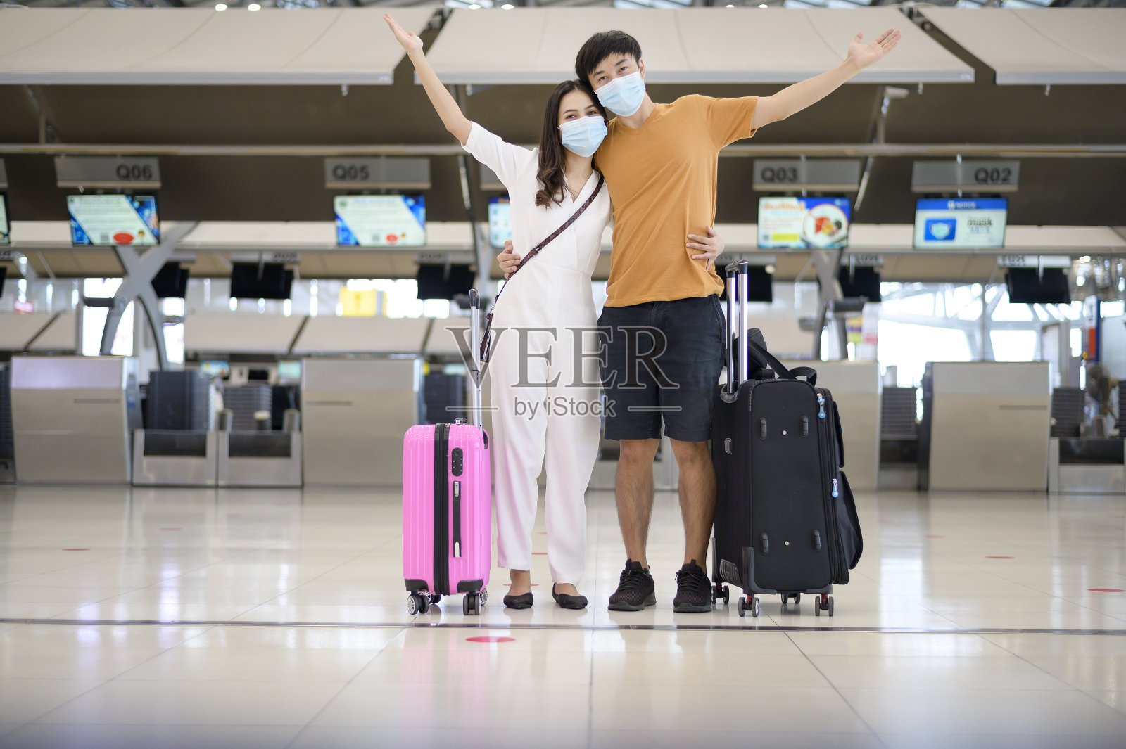 一对亚洲夫妇在国际机场戴着防护口罩、在新冠肺炎疫情下出行、安全出行、保持社交距离、新常态旅游理念。照片摄影图片