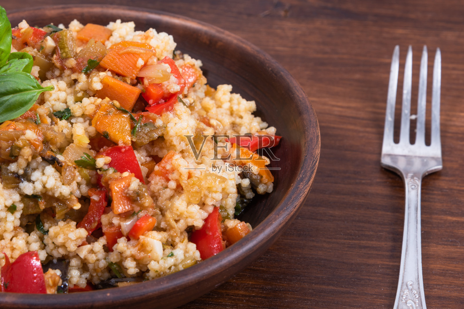 蒸粗麦粉炖蔬菜是摩洛哥、阿尔及利亚和突尼斯的一道菜肴。蒸粗麦粉和炖蔬菜混合在一个传统的黏土盘子里照片摄影图片