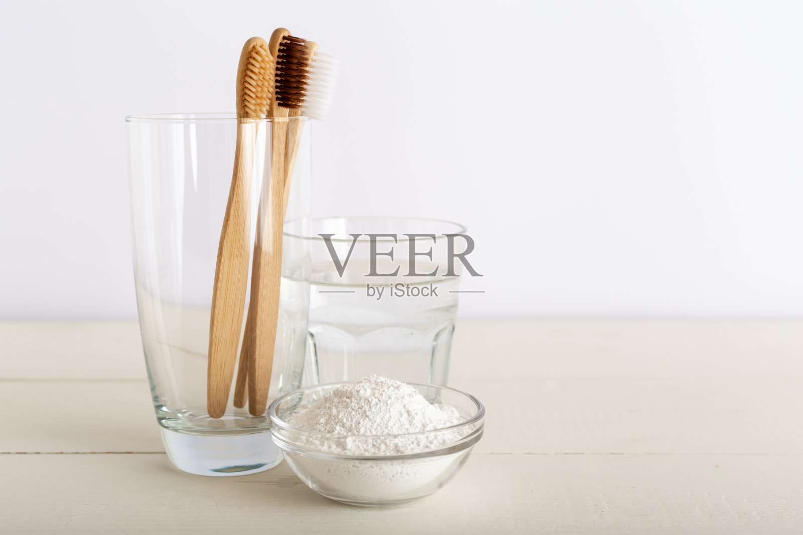 竹牙刷,一杯水,牙膏,白色背景上的牙粉。天然可降解竹牙刷。环保,零浪费,无塑料的理念。早上例行照片摄影图片