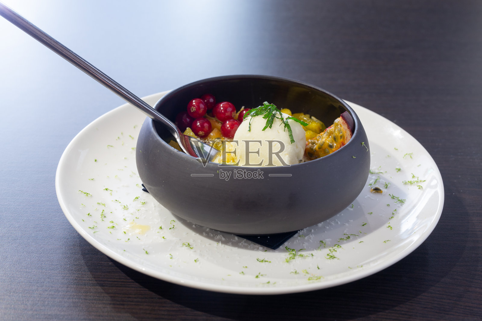 水果沙拉和冰淇淋放在一个黑色的碗里照片摄影图片