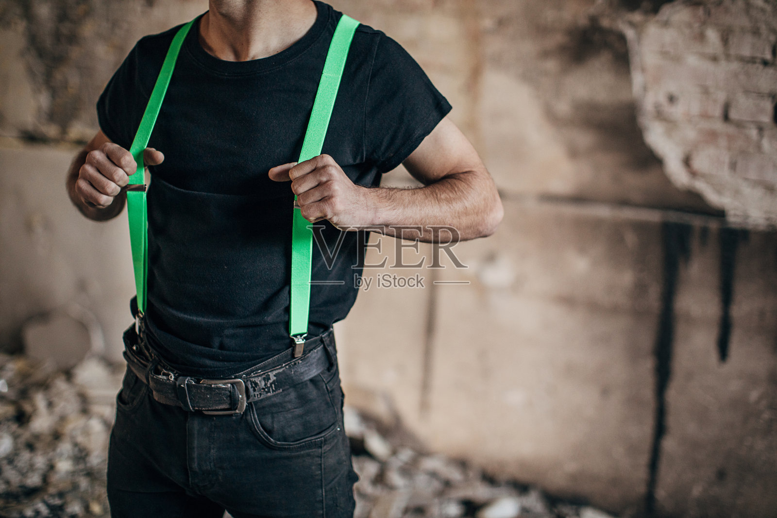 穿着绿色吊带裤的男性站在废弃的大楼里照片摄影图片