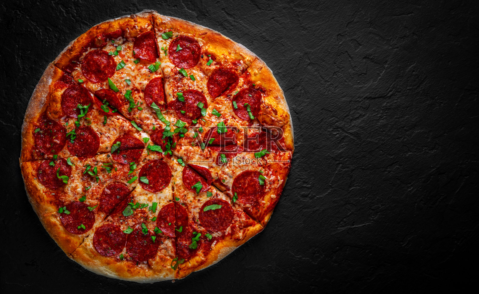 意大利辣香肠披萨配马苏里拉芝士,意大利腊肠,番茄酱,胡椒,香料。意大利披萨在深灰色的黑色石板背景照片摄影图片