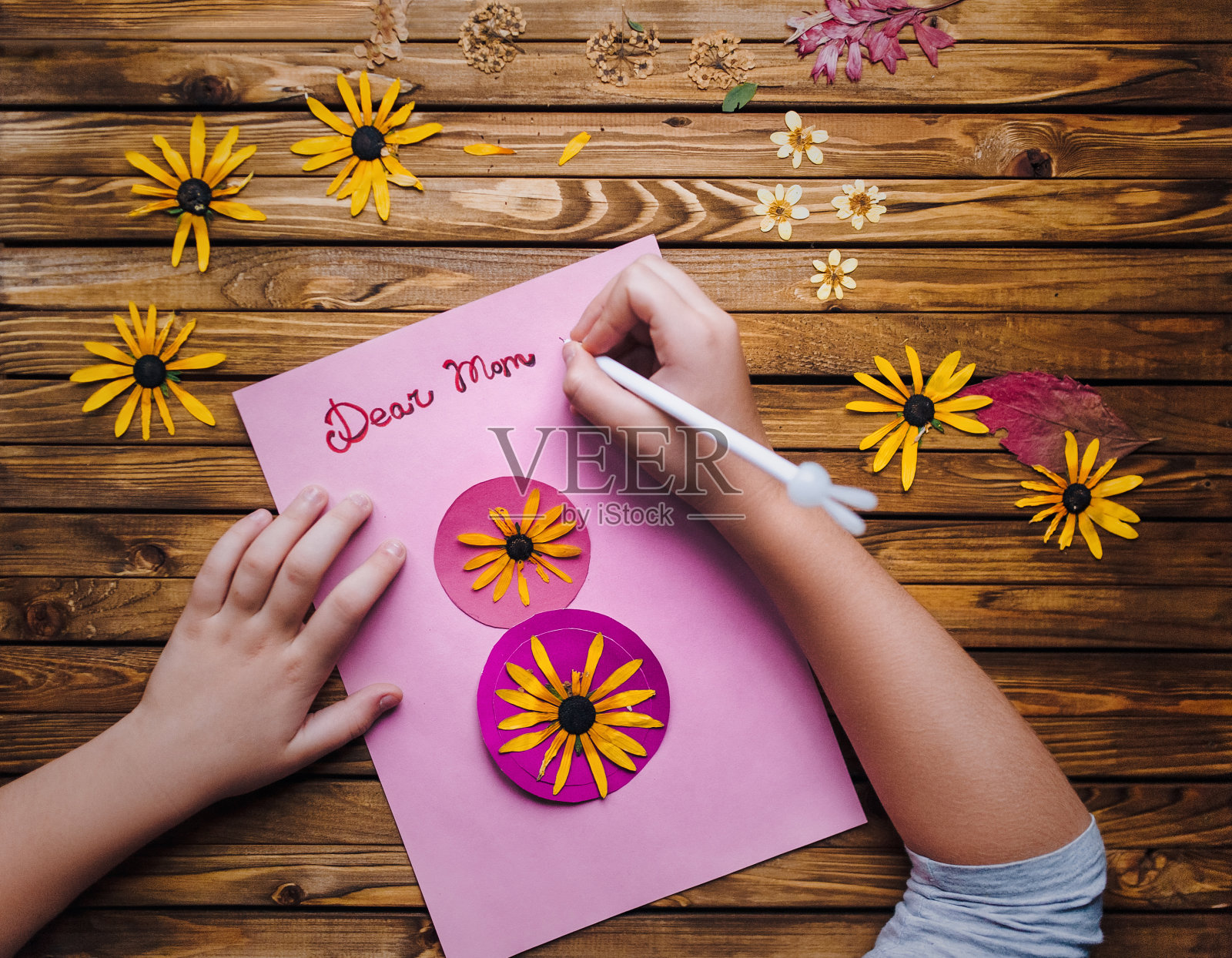 为了庆祝3月8日的节日,孩子们会亲手制作一张明信片送给她的母亲。孩子的创造力,手工制作的。亲爱的妈妈。插花。照片摄影图片