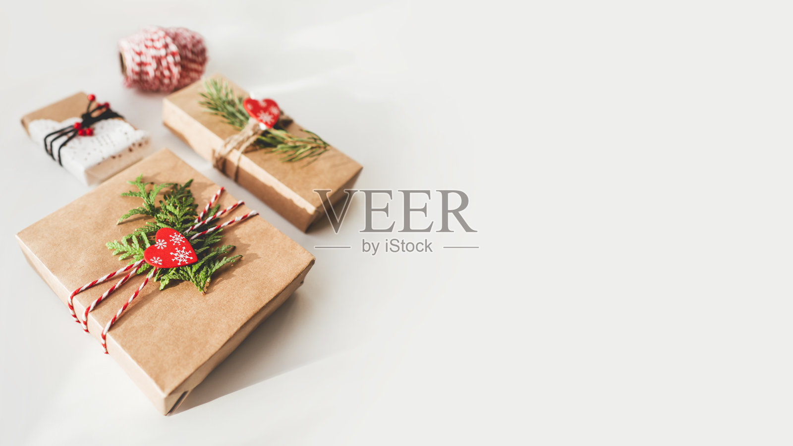 圣诞DIY礼物包在牛皮纸与冷杉树枝和红心。新年礼物上的装饰品。节日的背景。寒假的精神。带有拷贝空间的横幅。照片摄影图片