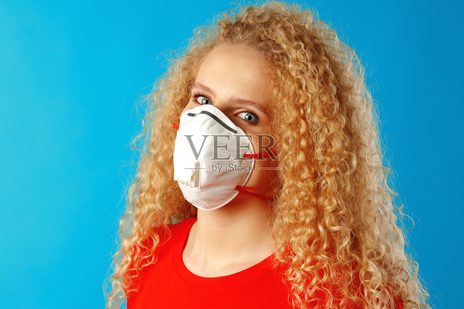 美丽的年轻女子,一头卷发,戴着医用口罩照片摄影图片