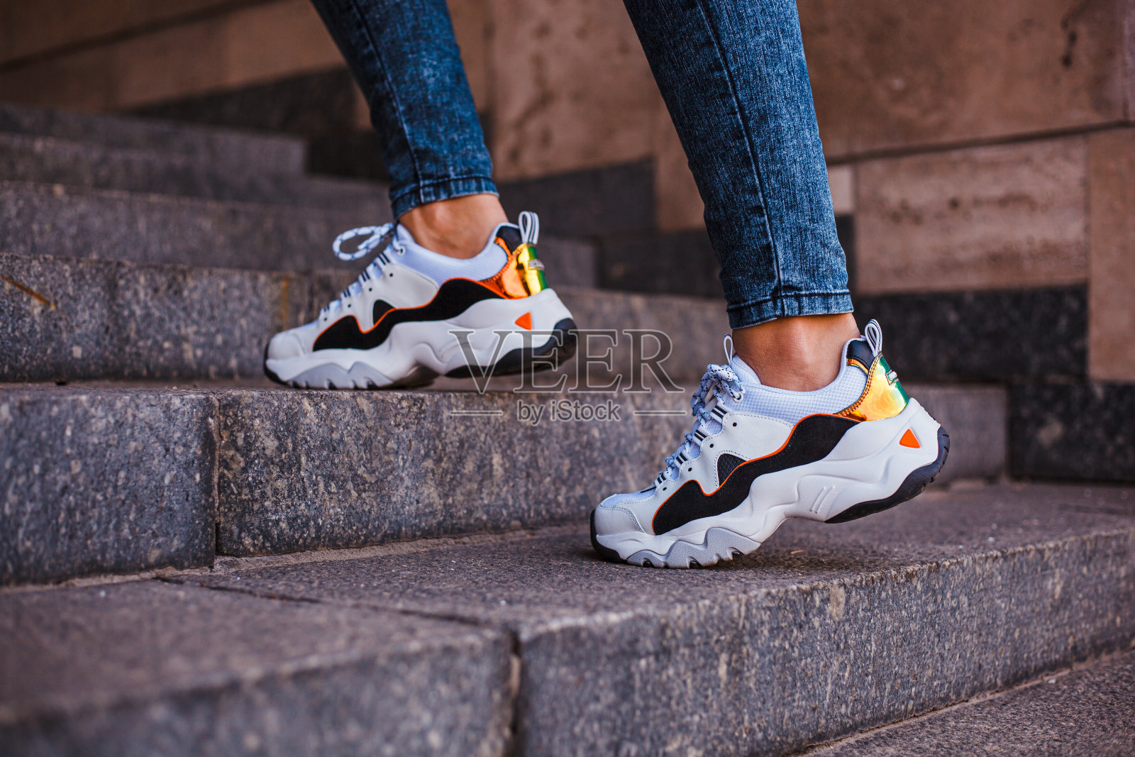 在街上的大理石楼梯上,穿着牛仔裤的女性脚蹬黑色运动鞋照片摄影图片