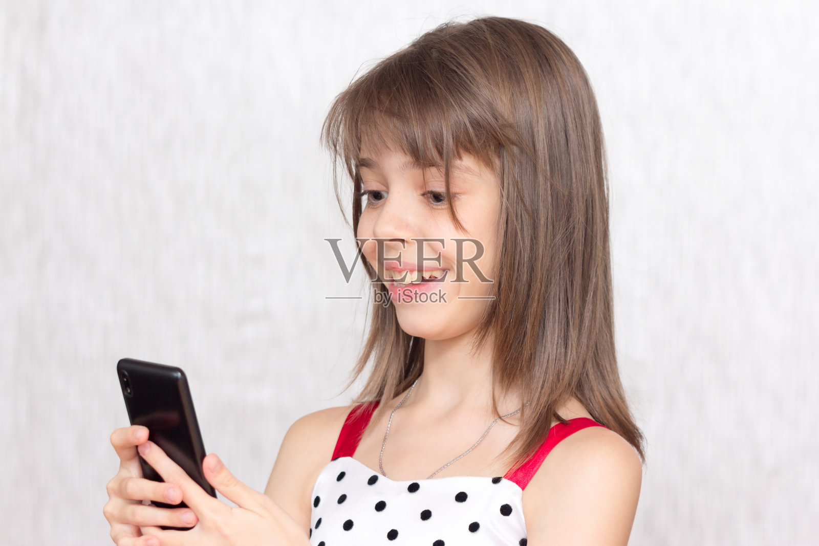 快乐的小女孩在她的智能手机上看娱乐材料。照片摄影图片