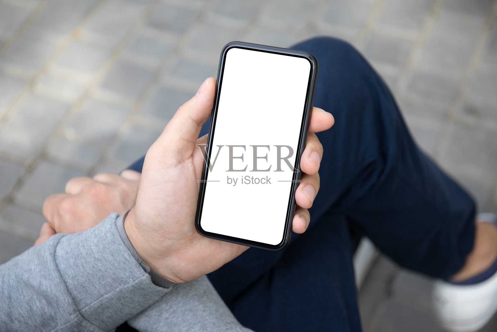 男人的手在街上拿着电话与孤立的屏幕照片摄影图片