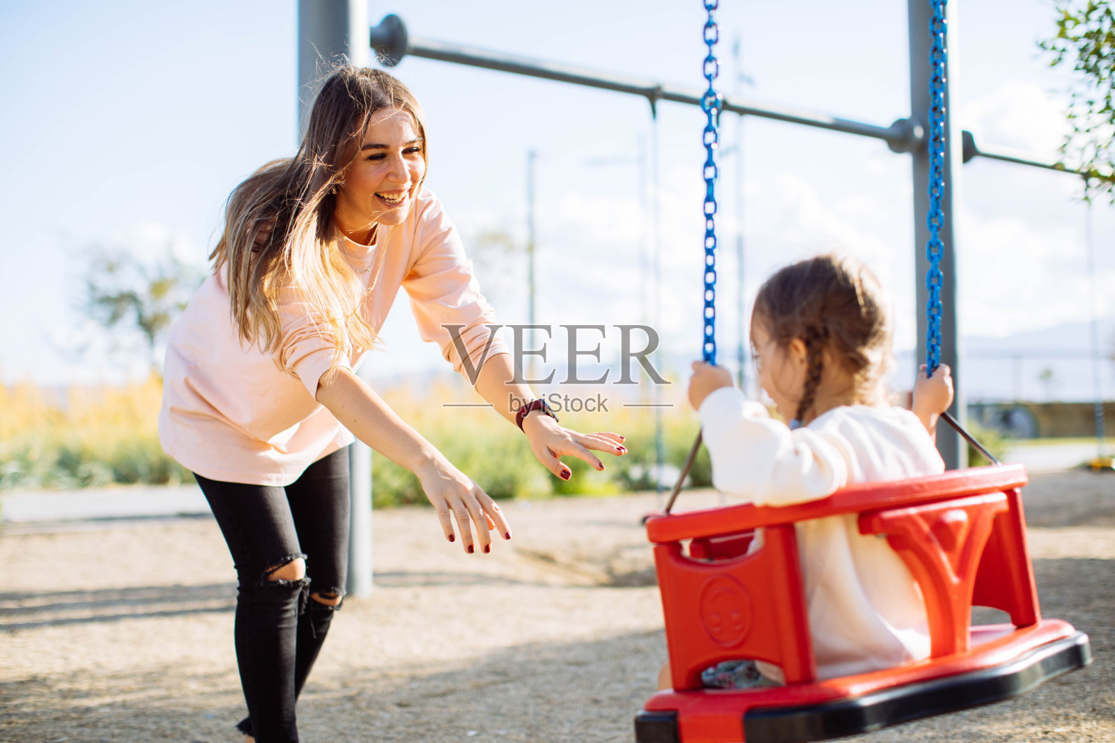 妈妈推着女儿在公园里荡秋千照片摄影图片