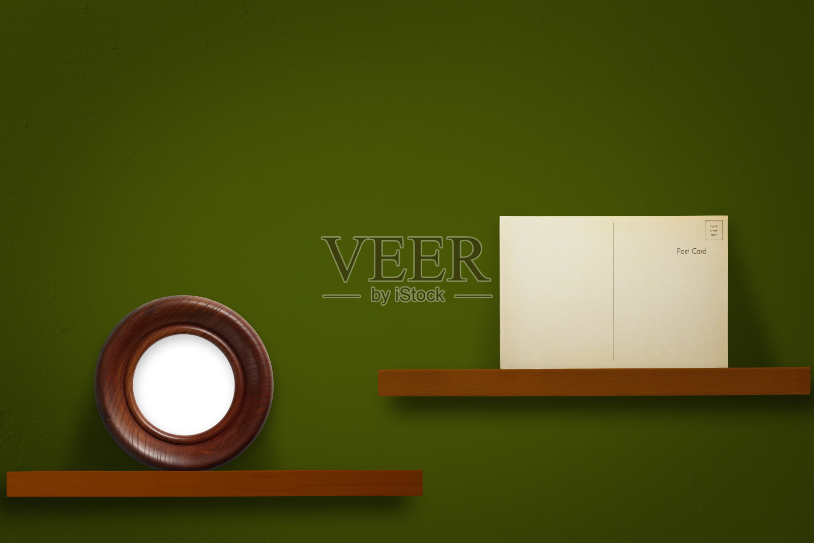空白的古董明信片和空白的圆形相框放在一个木架子上,背靠深绿色的墙壁照片摄影图片