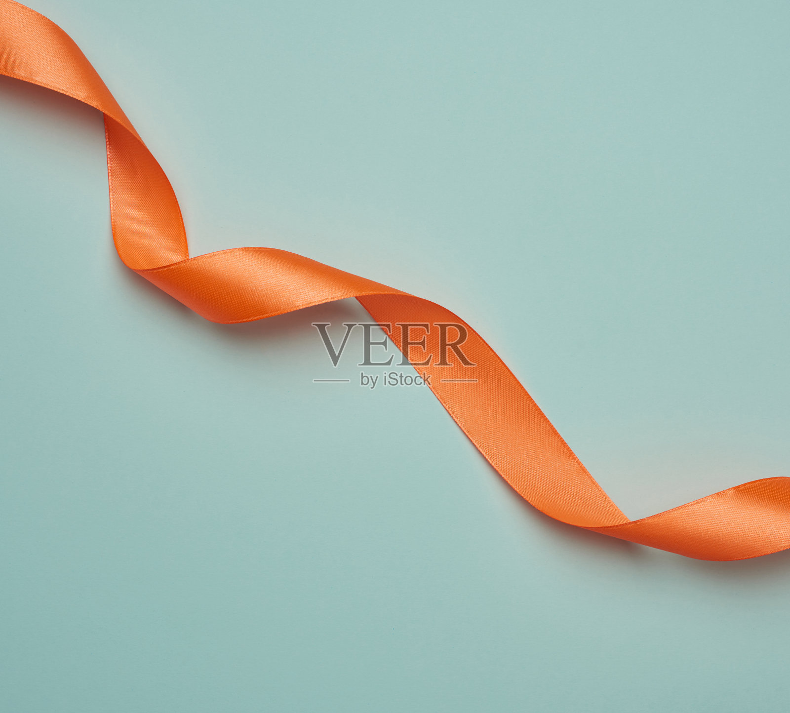 蓝色背景上扭曲的橙色丝带照片摄影图片