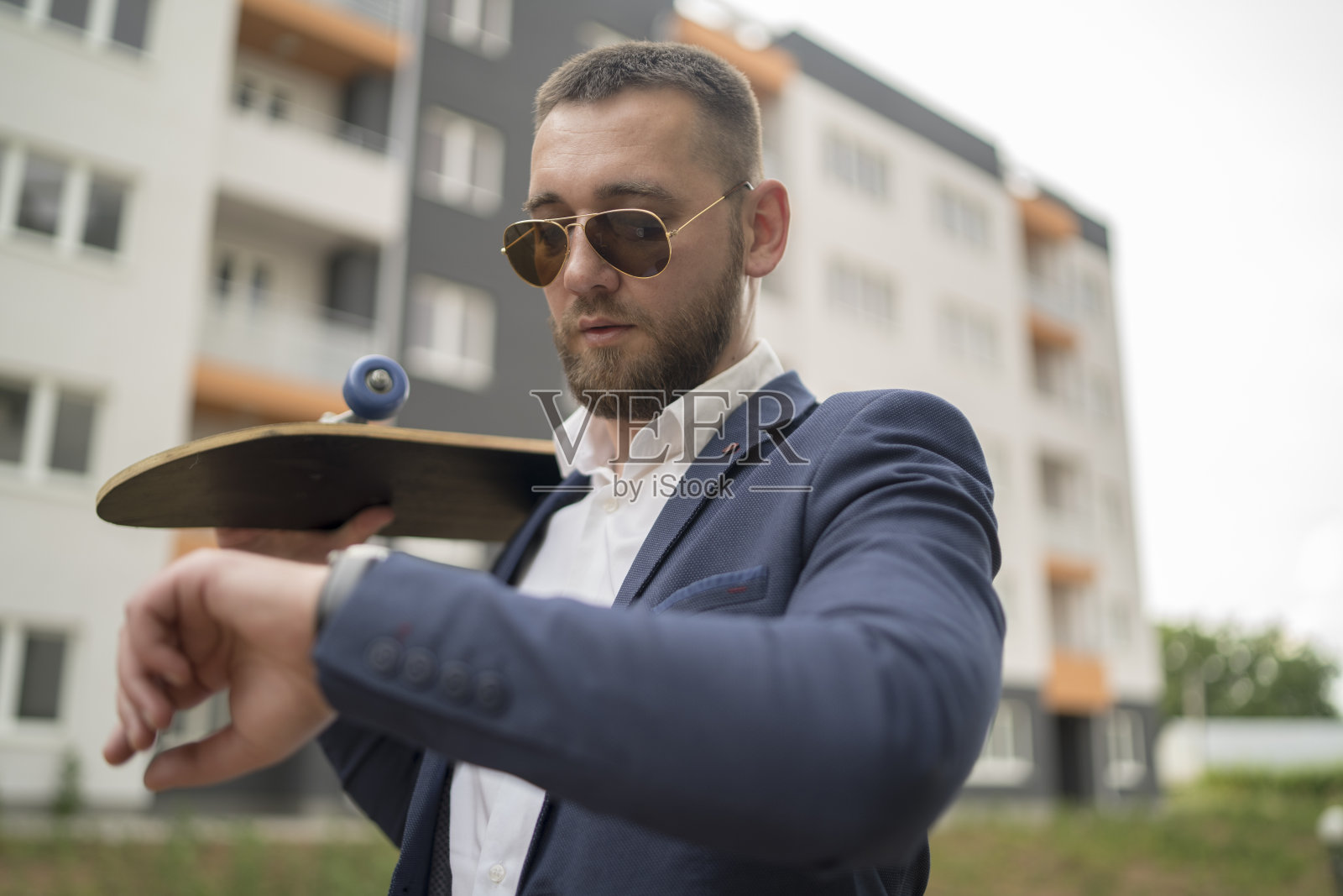 商人与滑板检查他的手表上的时间照片摄影图片