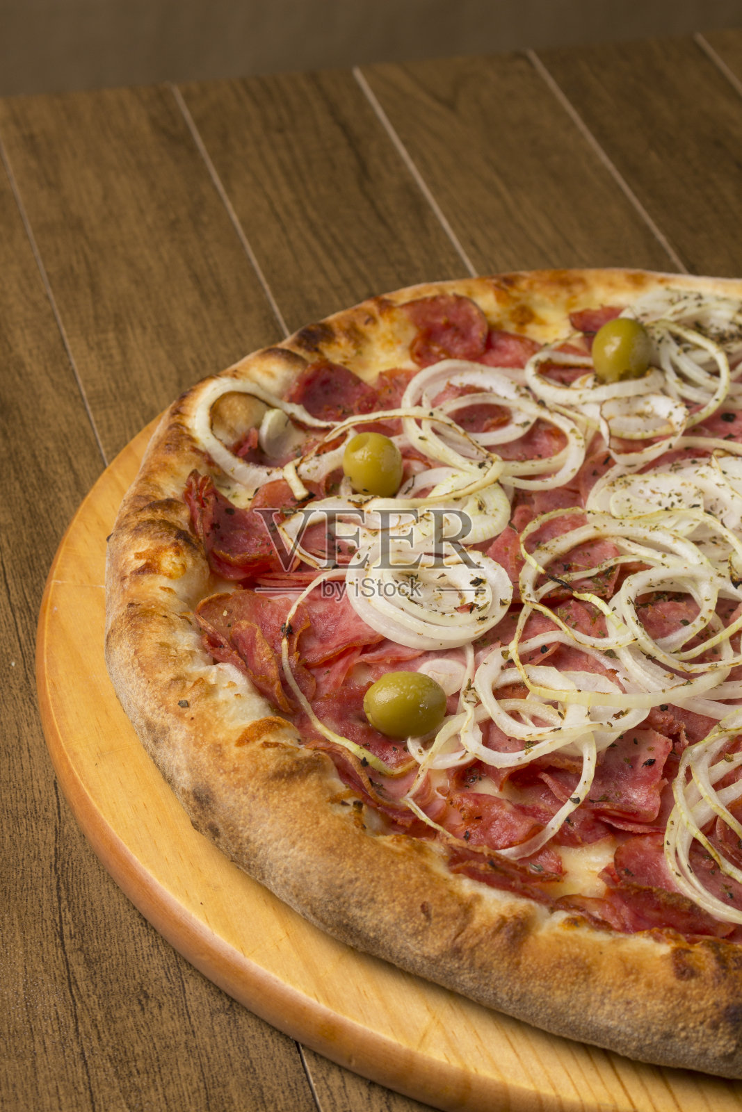 意大利辣香肠披萨,洋葱片,马苏里拉奶酪和绿橄榄。餐馆和披萨店的照片。照片摄影图片