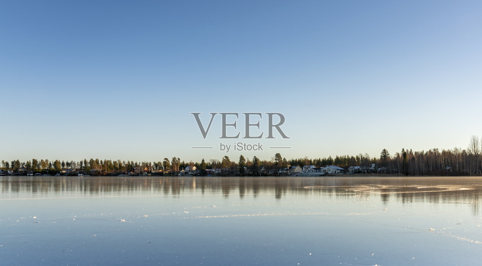 瑞典的村庄坐落在很远的地方,在晶莹剔透的冰湖旁边。表面看起来像一面巨大的镜子,晴朗的天空,非常寒冷的冬天,瑞典北部照片摄影图片