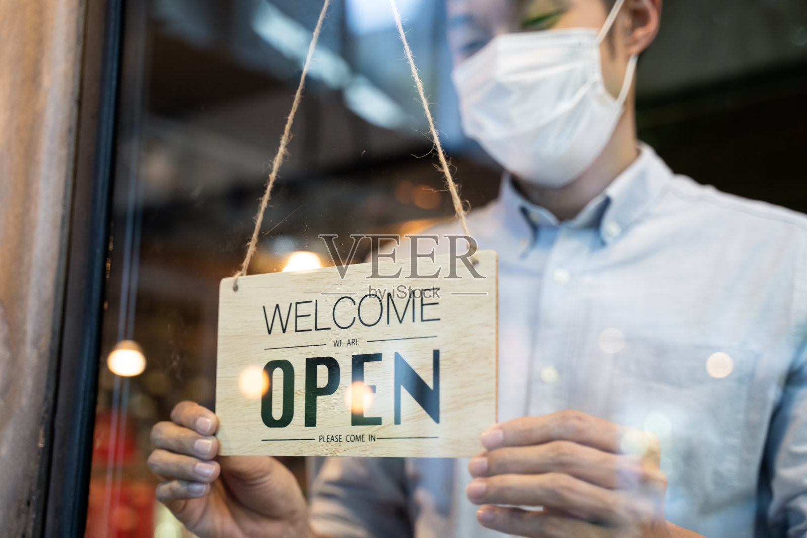 新冠肺炎疫情隔离结束后,咖啡馆、餐厅和企业重新开业。一名戴面罩的男子将一家商店的招牌从关门变为开门。新冠肺炎封锁后的小型食品店生意。照片摄影图片