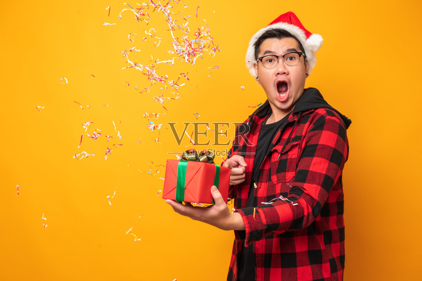 快乐兴奋的亚洲人在新年的圣诞节拿着礼物盒在孤立的黄色背景。从圣诞老人那里得到礼物的男人。照片摄影图片