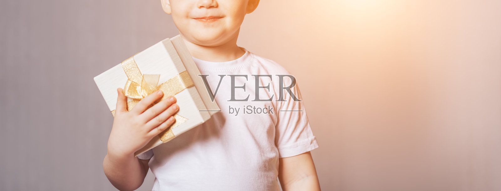 漂亮的小男孩穿着白色t恤,手里拿着礼物照片摄影图片