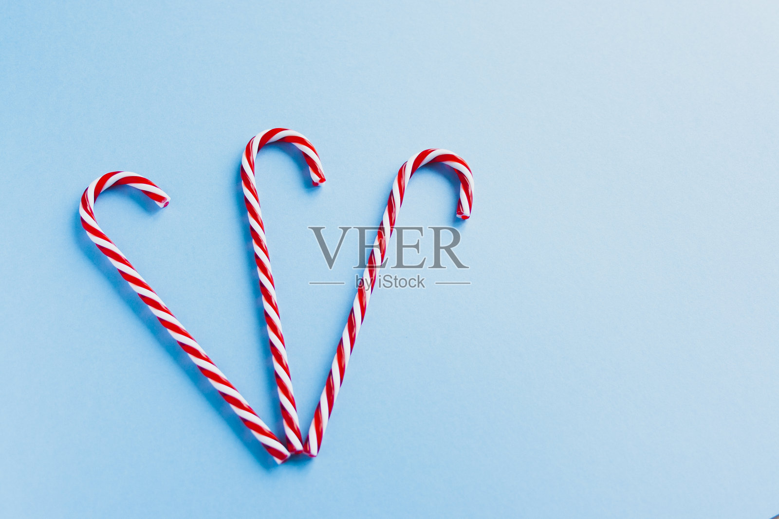 圣诞组成。圣诞三根棒棒糖平躺着,顶视图上是淡粉色的背景。节日庆祝贺卡与复制空间的文字。圣诞背景糖果手杖和冷杉枝,横幅,明信片照片摄影图片