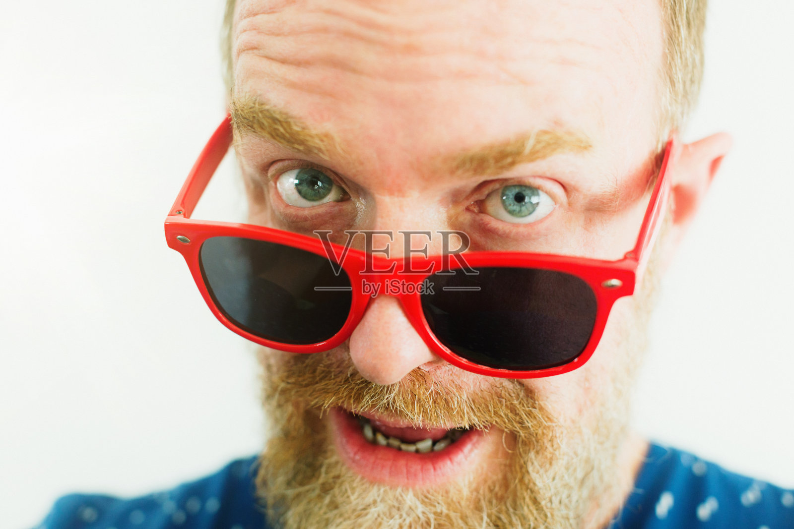 一个戴着新奇红色太阳镜的中年男人好奇地看着你照片摄影图片