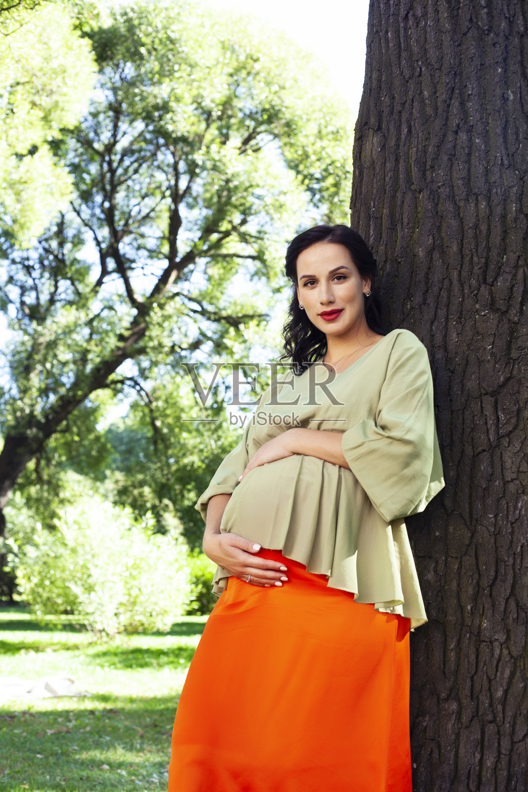 年轻漂亮的黑发孕妇户外在绿色公园快乐的微笑,生活方式人们的概念照片摄影图片