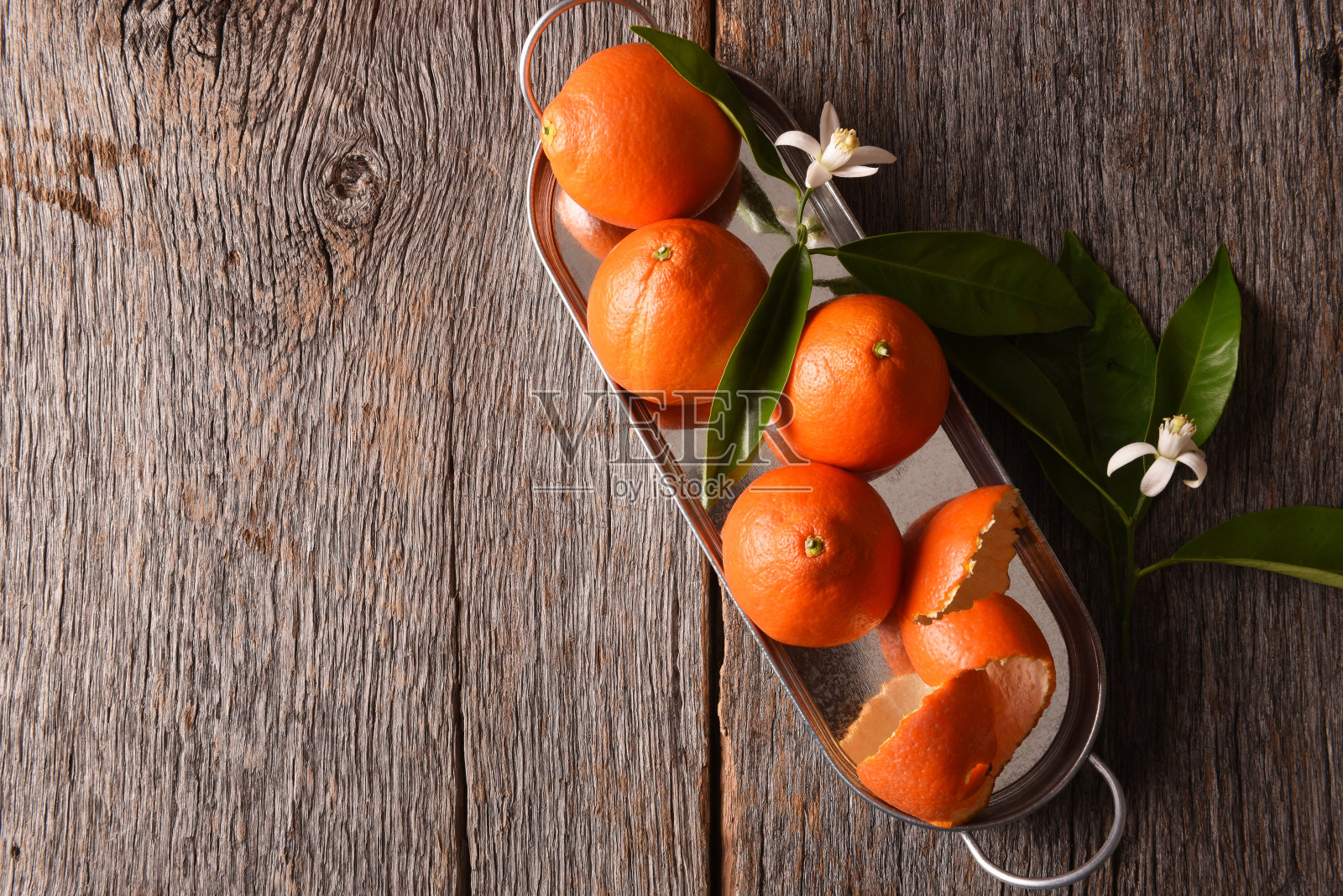 橘柚在金属托盘上,叶子和橙色的花朵,在木材背景与复制空间照片摄影图片