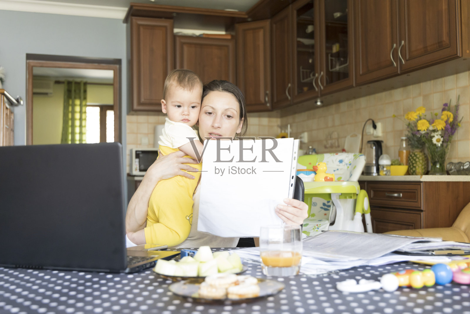 居家办公一个职业母亲照看她的孩子。照片摄影图片