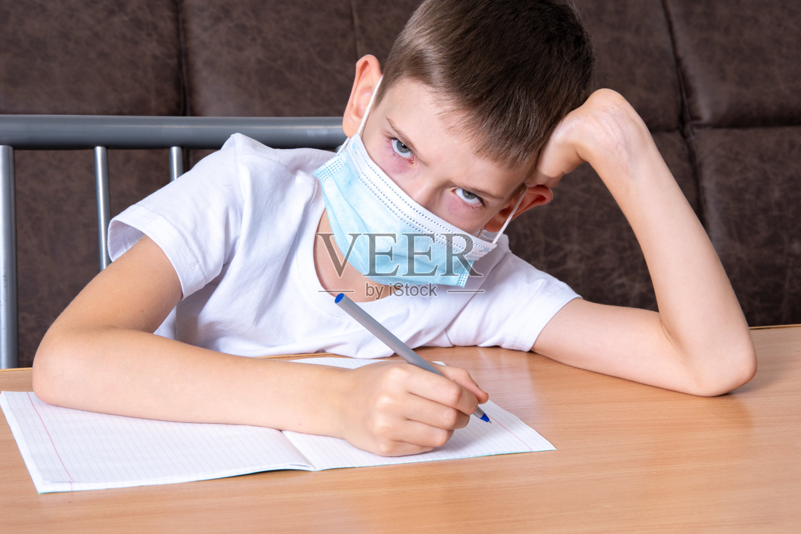 一个男孩戴着防护面具不高兴地看着你,孩子不想在家在线学习照片摄影图片