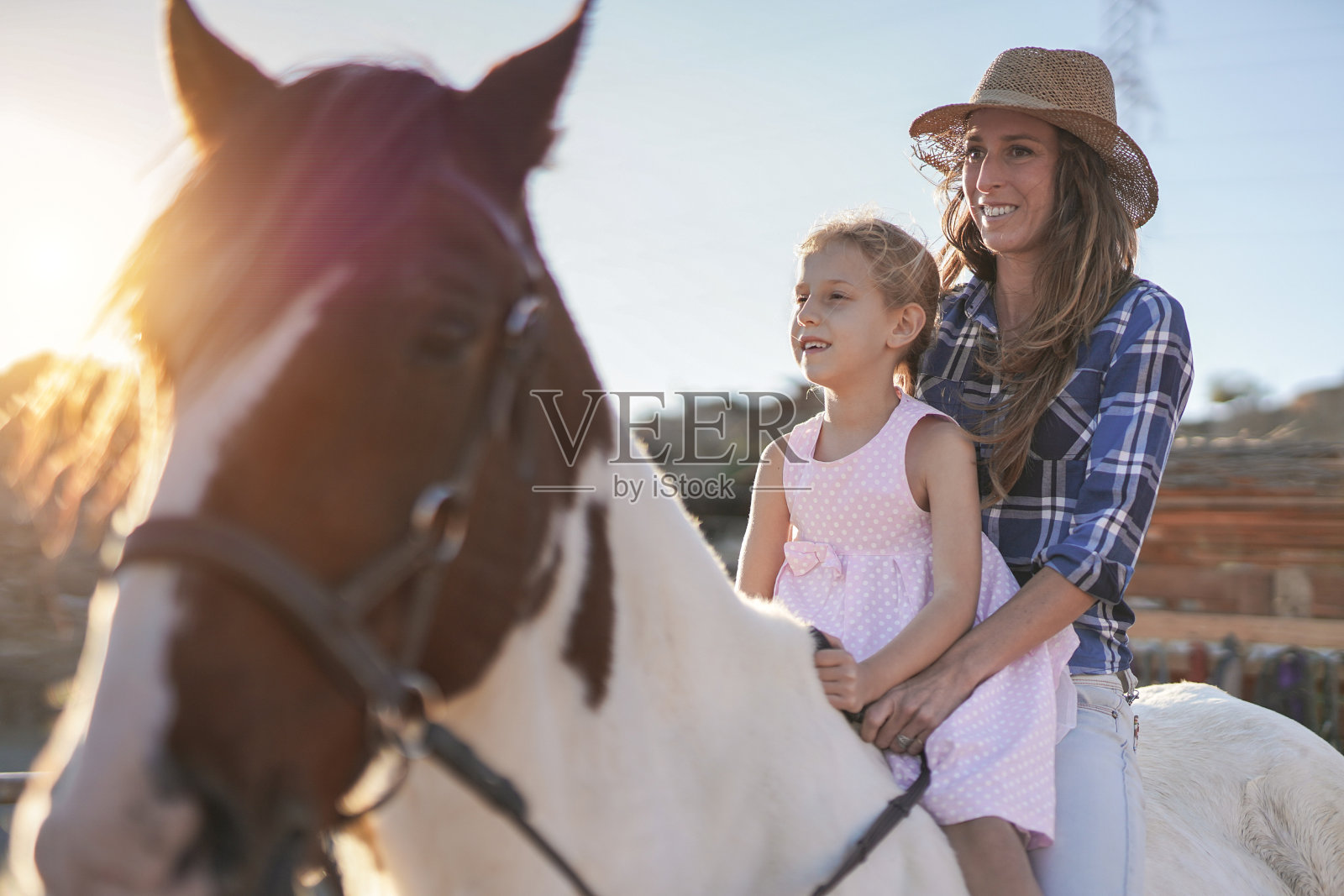 母亲和女儿在牧场户外骑马-动物的爱照片摄影图片