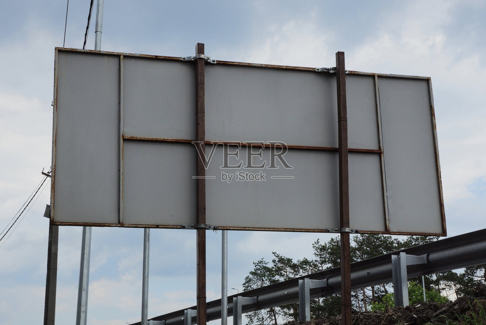 街道上有一块灰色的长方形金属广告牌,上面是棕色的铁柱子照片摄影图片