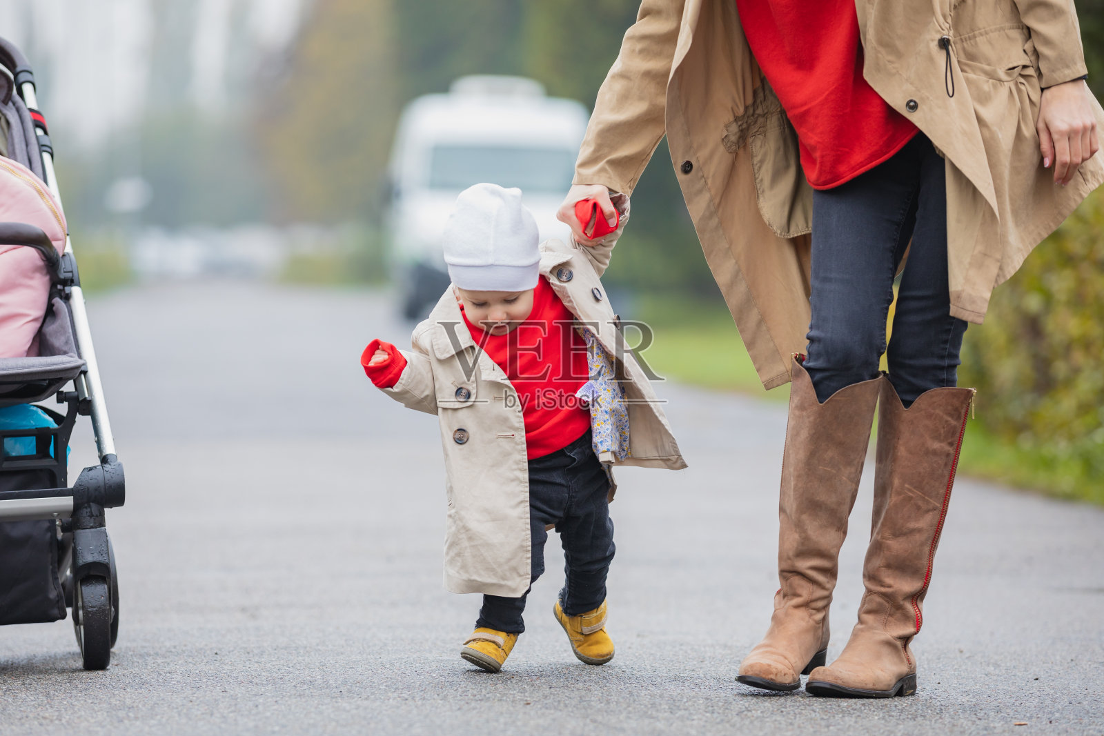 可爱有趣快乐的宝宝在秋天花园的绿色草坪上迈出第一步,妈妈牵着他的手支撑着学习走路照片摄影图片