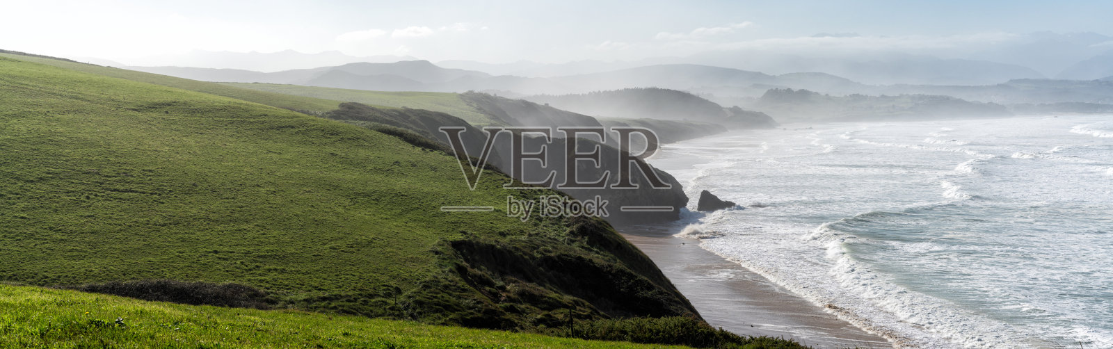 绿色的长满草的悬崖向下延伸到西班牙北部的海岸照片摄影图片