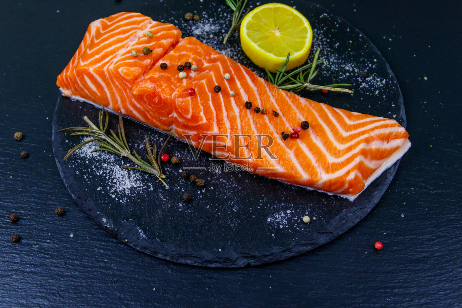 生鲑鱼片配上香料放在黑石板上照片摄影图片