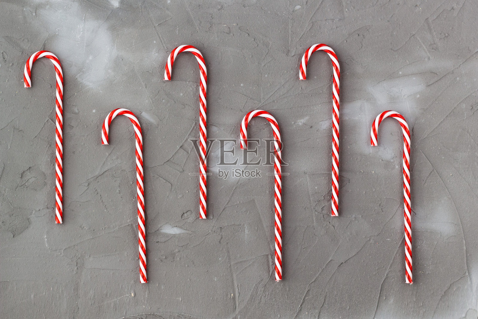 红色和白色的糖果拐杖在灰色背景的边界。圣诞音乐会照片摄影图片