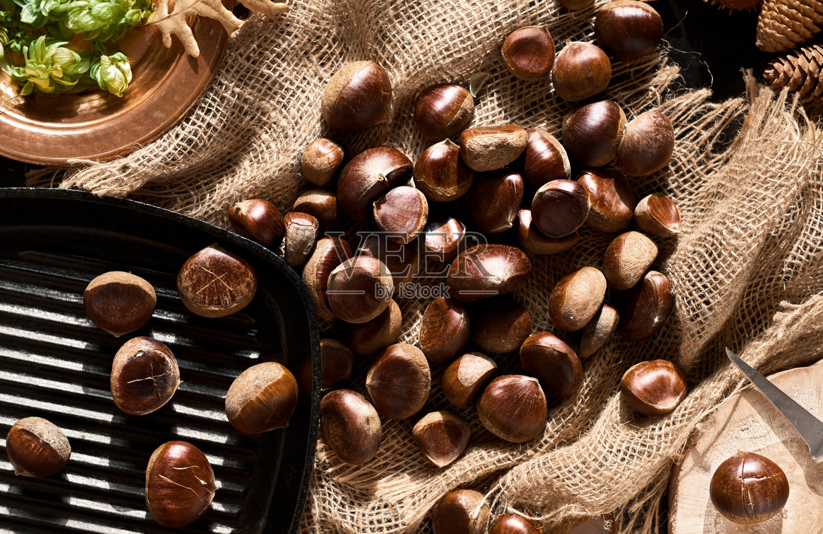 粗麻布上的生栗子,背景为黑色,有拷贝空间,准备在平底锅中烘烤。前视图。栗子是圣诞节或节假日的应季菜肴照片摄影图片