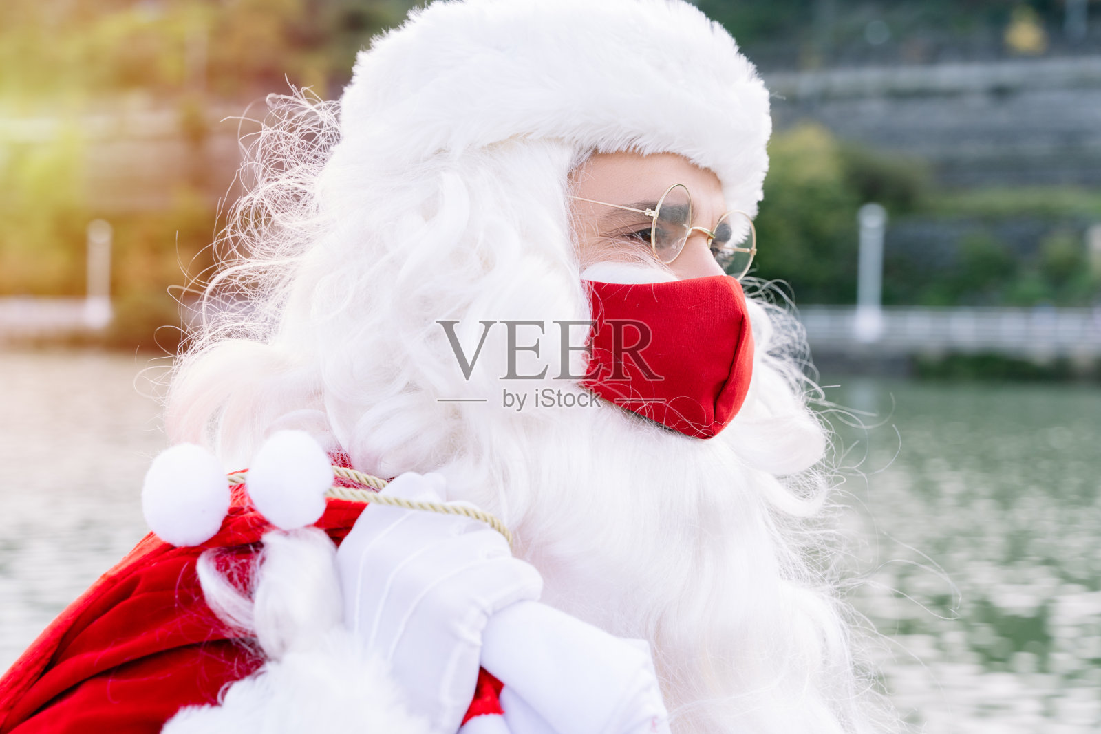 2020年圣诞节,由于新冠肺炎大流行,圣诞老人肩上扛着礼物袋走在街上照片摄影图片