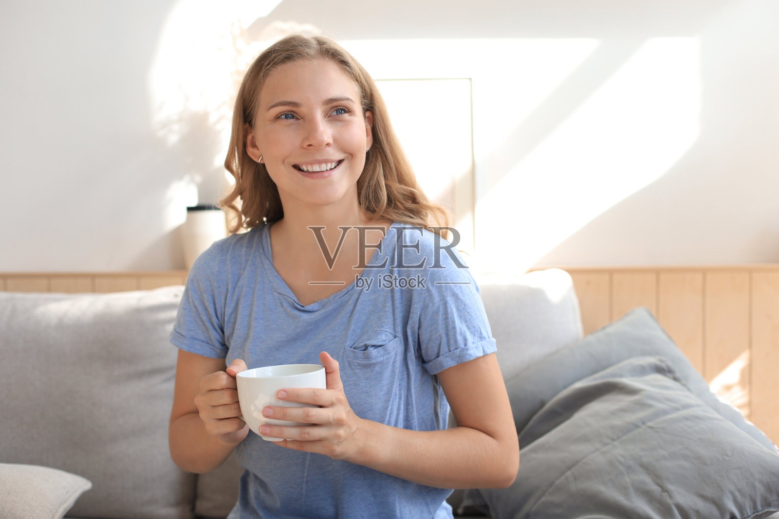 坐在扶手椅上喝咖啡的年轻女子。照片摄影图片