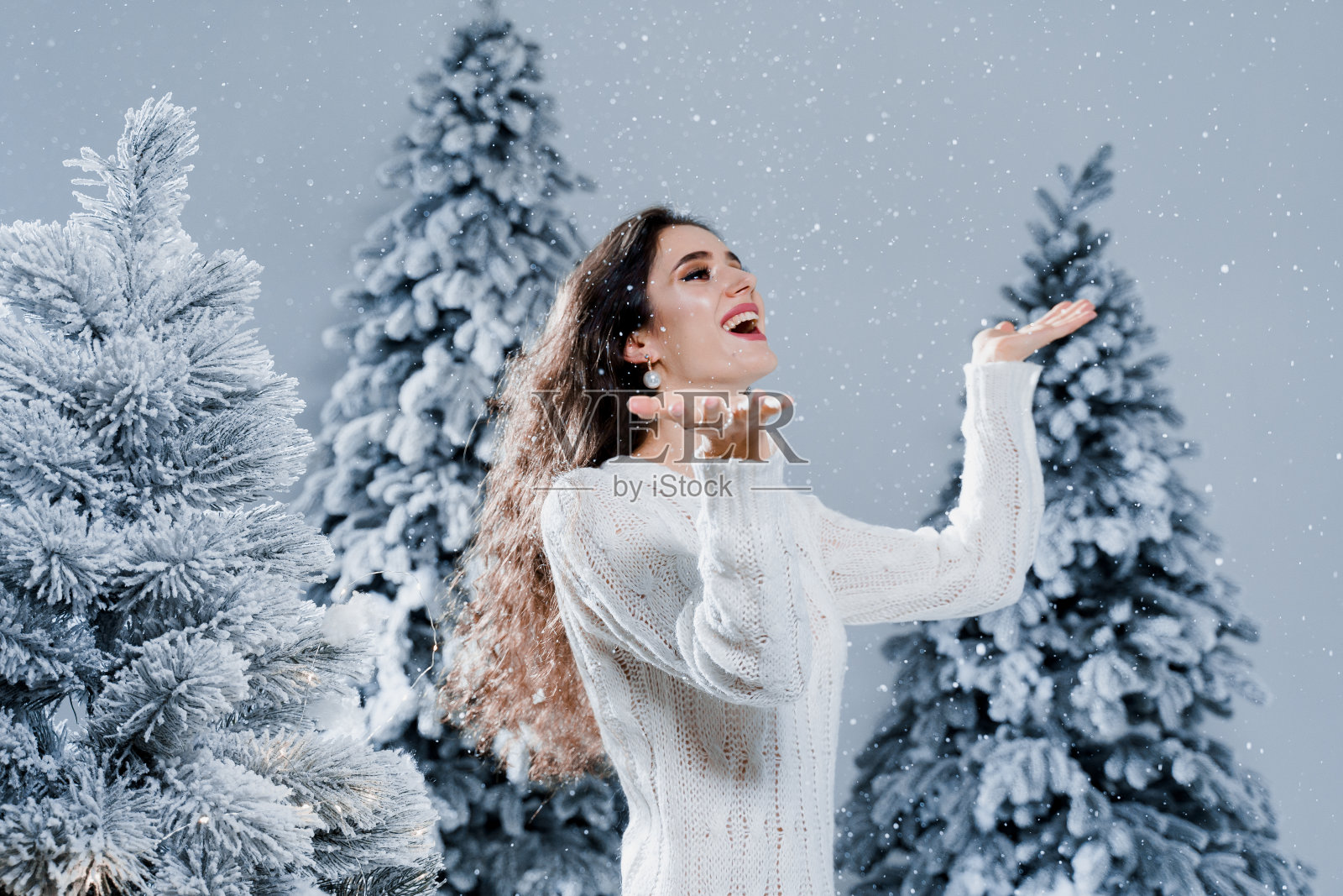 32、快乐女孩微笑,触碰新年除夕飘落的雪花。年轻女子靠近大雪杉在圣诞节前的冬天照片摄影图片