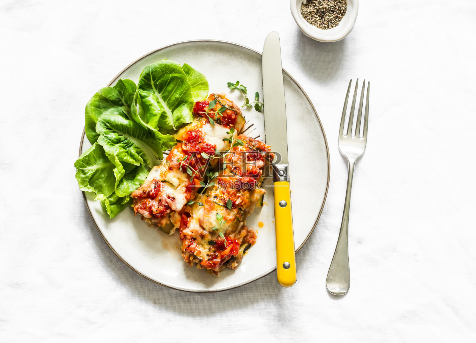 素菜烤西葫芦馅干瓜,配上番茄酱、百里香和马苏里拉芝士,背景明亮,俯视图照片摄影图片