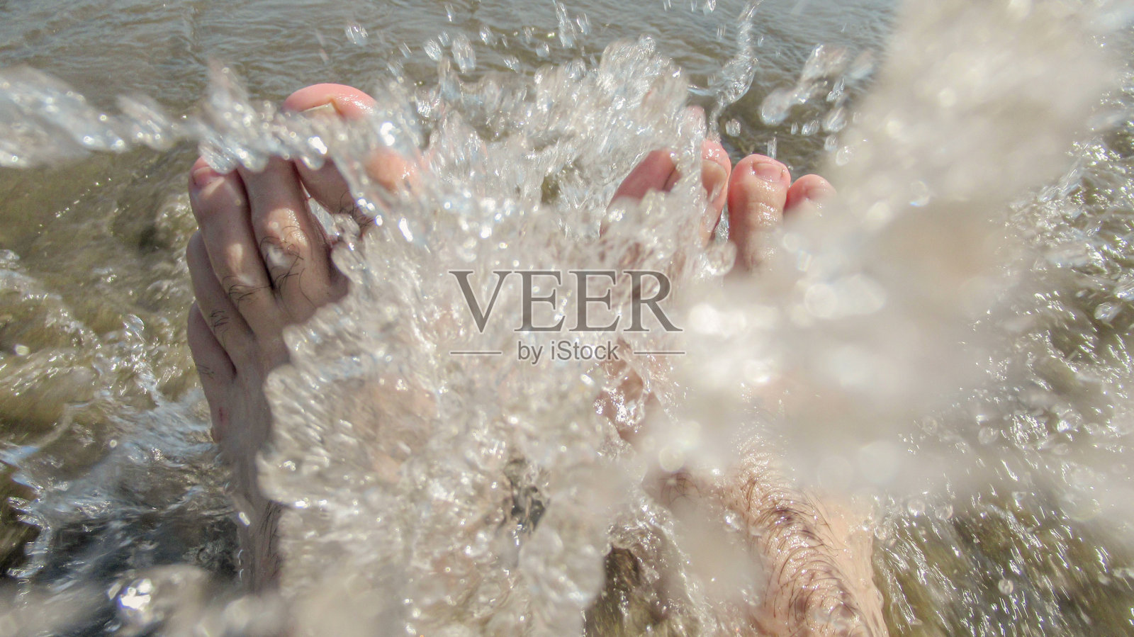 在公共海滩上,海水溅到一个年轻白人的脚上照片摄影图片